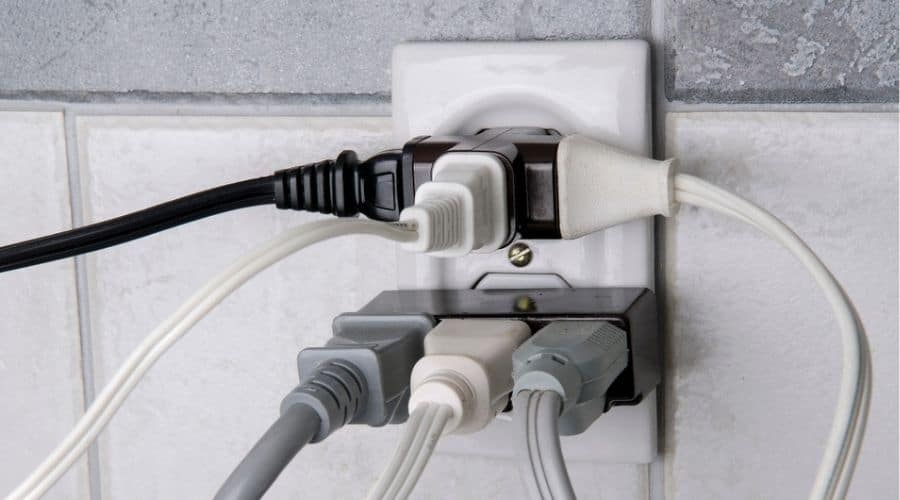 A wall outlet overloaded with plugs