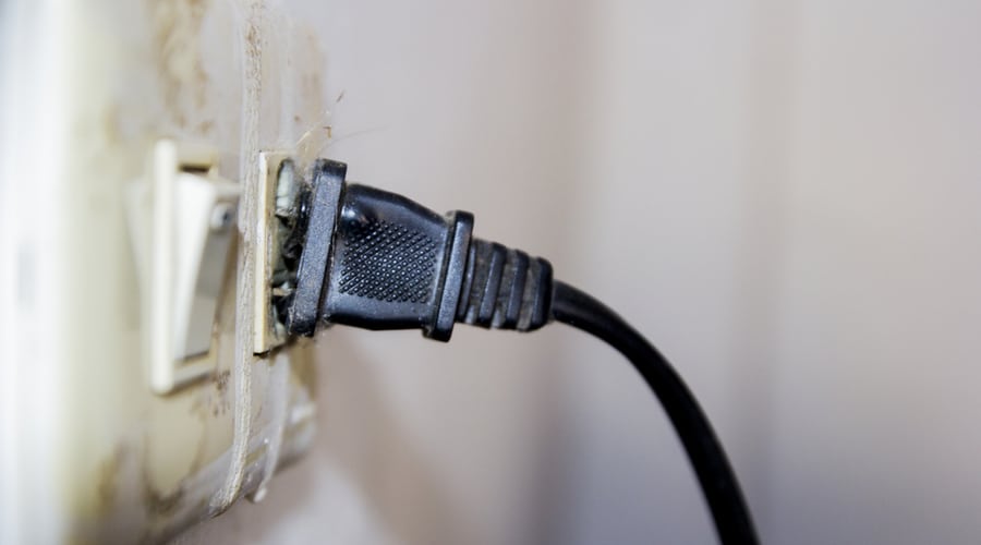 A damaged electrical outlet with frayed wires and charing.