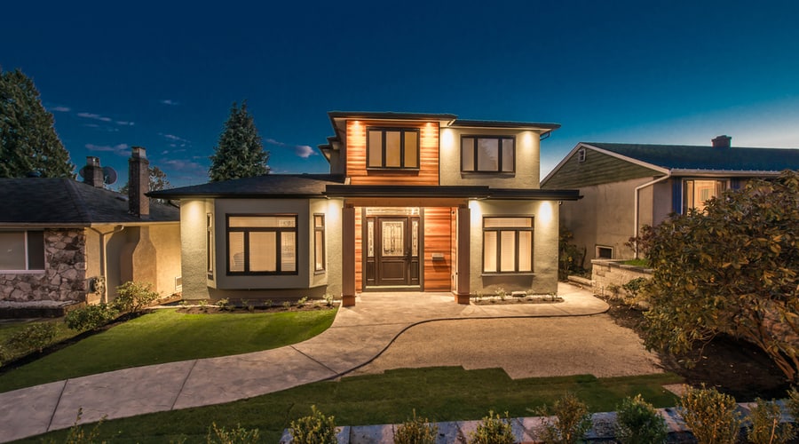 A suburban house with outdoor lighting at night.