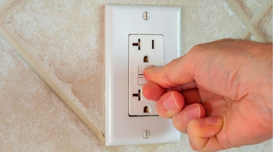 Close up of somebody resetting a GFCI outlet