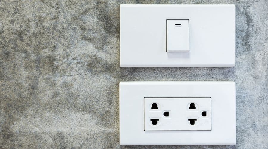 A light switch and a pair of electrical outlets on a concrete wall