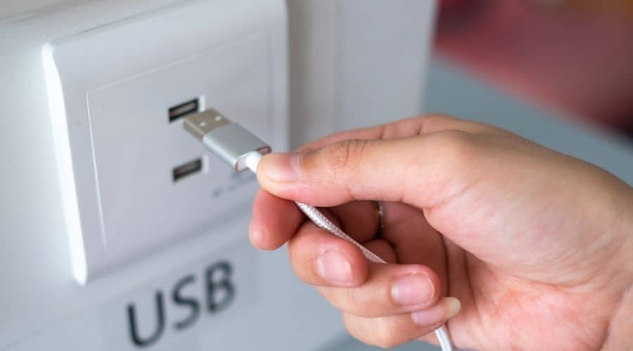 Close-up of somebody plugging a cord into a USB outlet