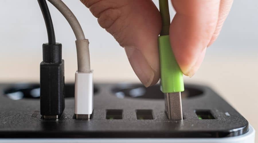 Close-up of a hand plugging a charger into a multi-port USB outlet.