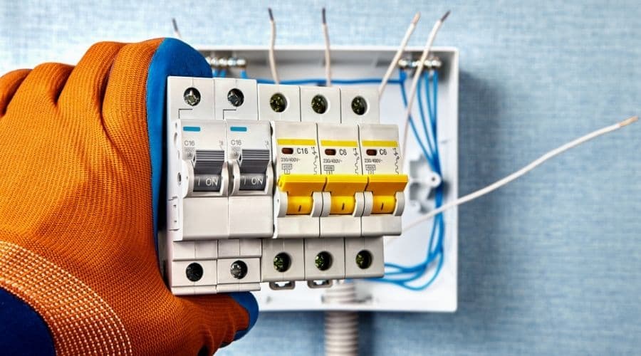 A gloved hand installing a circuit breaker in an electrical cabinet