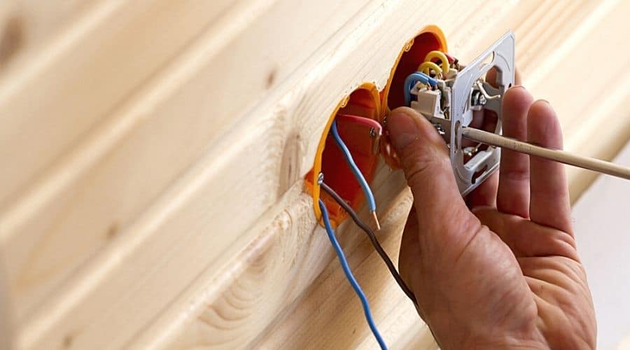 Close-up of somebody installing an outlet into a wood-paneled wall