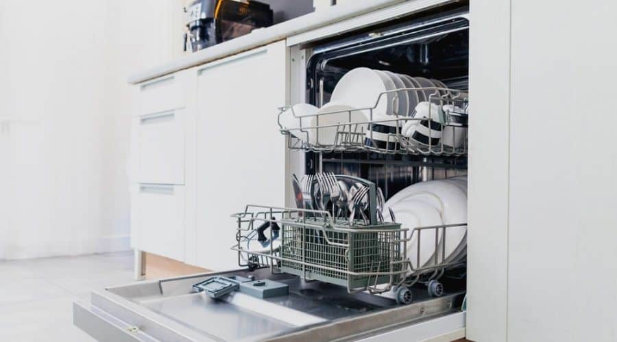 A full dishwasher in a kitchen with white cupboards.