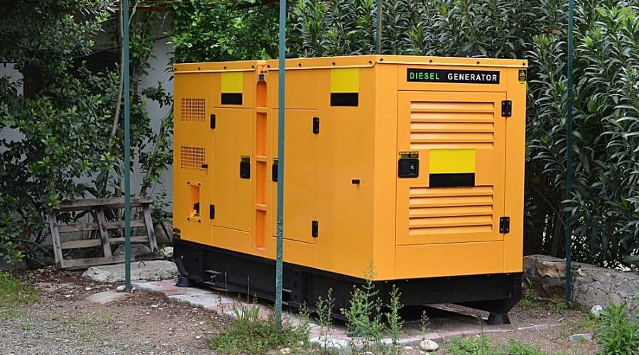 A large, yellow diesel generator in a yard