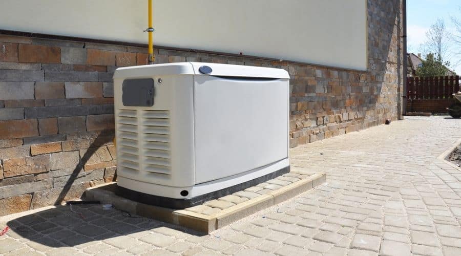 A white generator along the side of a house