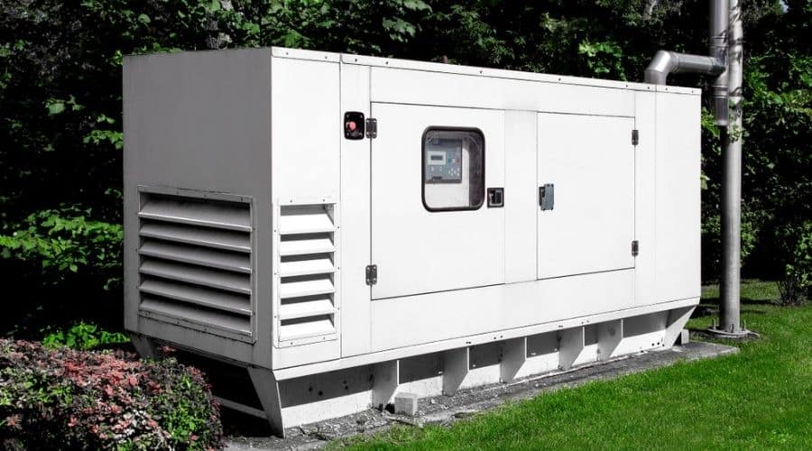 A large, white emergency generator in a yard