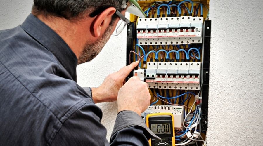 A technician fixing a cable in the terminal of a circuit breaker