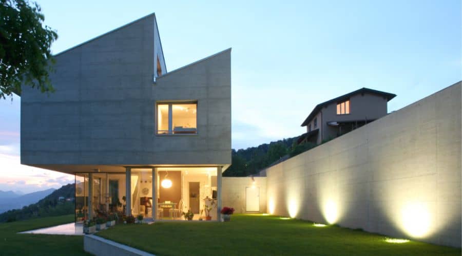 A large modern home with uplighting in the yard