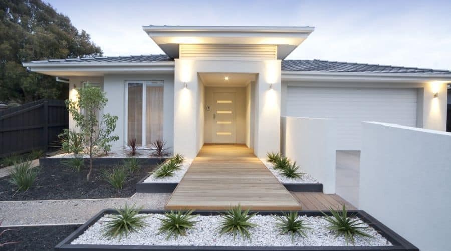 A white, modern home featuring exterior lighting
