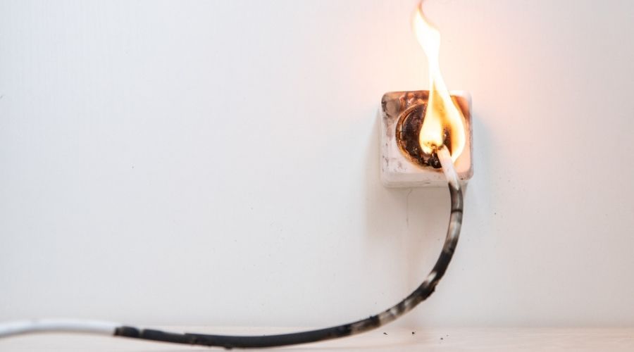 An electrical fire originating from an outlet on a white wall