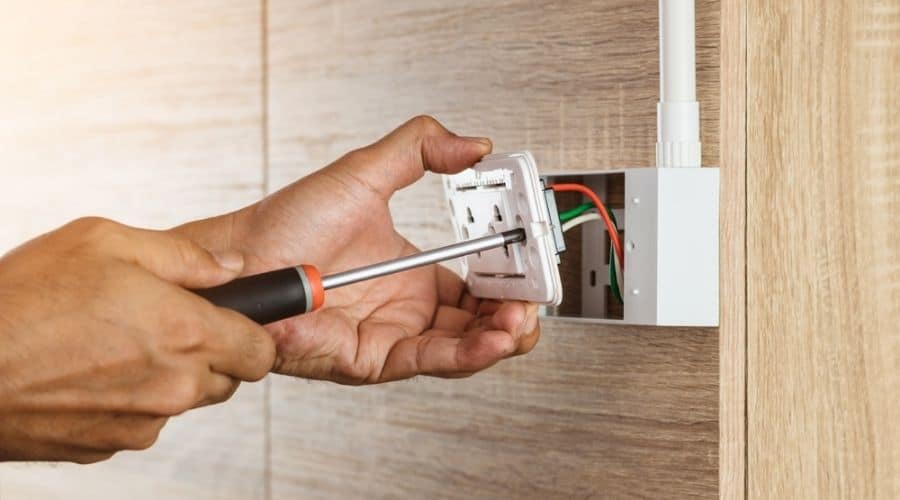 Close-up of somebody unscrewing a white outlet so it can be replaced