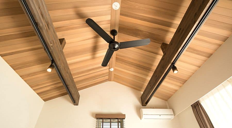 a black ceiling fan against a wooden cathedral ceiling