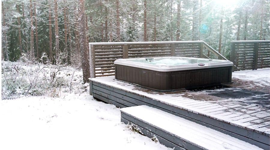 an outdoor hot tub on a wooden deck during the winter