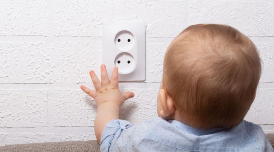 a baby reaches for an outlet