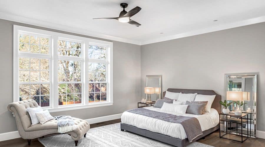 a grey bedroom with a black fan on the ceiling