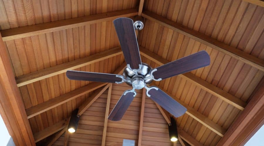 an indoor ceiling fan installed on a high wooden ceiling