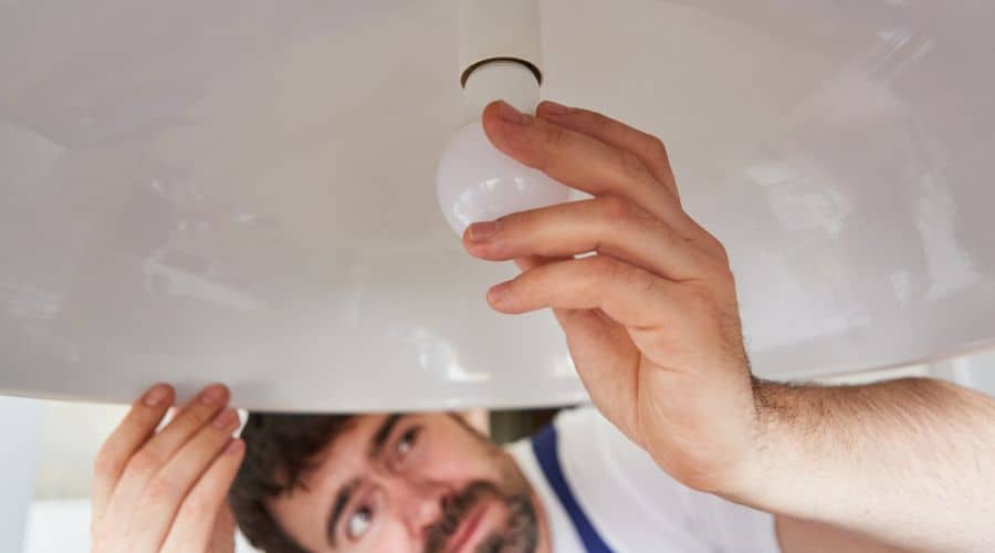 a man screws a lightbulb into a lamp