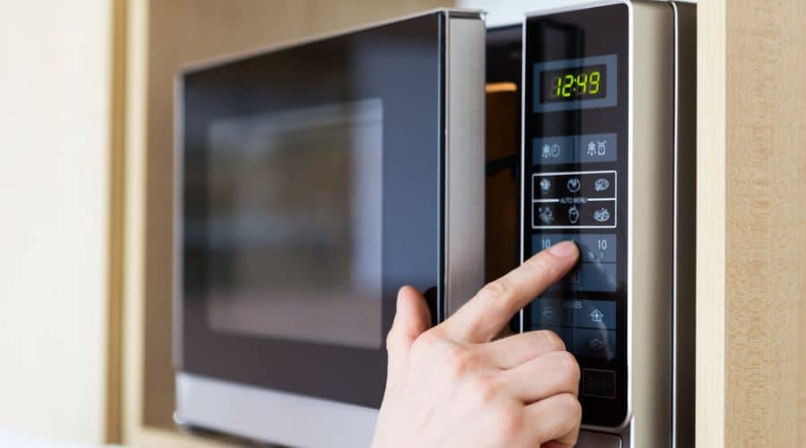 close up of a hand operating a microwave oven